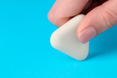 Photo of Woman using eraser on light blue background, closeup. Space for text