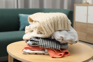 Photo of Stack of different used clothes on coffee table indoors, closeup