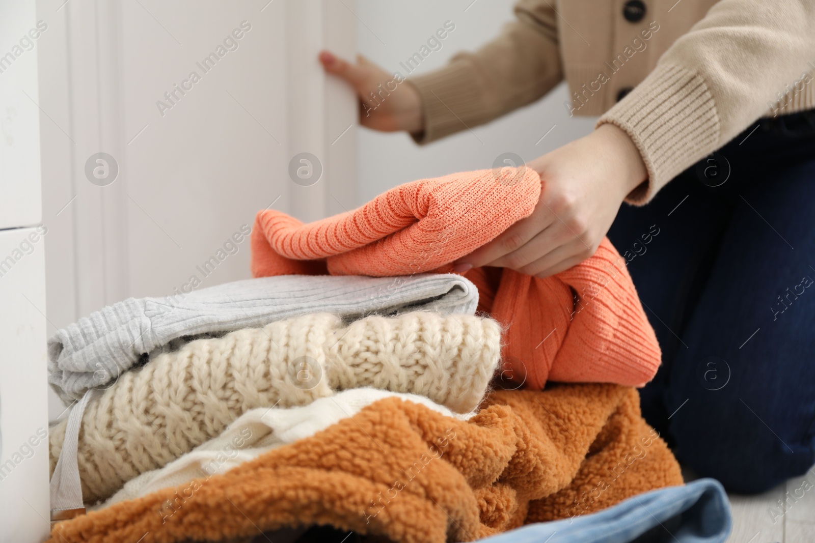 Photo of Woman with pile of different used clothes indoors, closeup