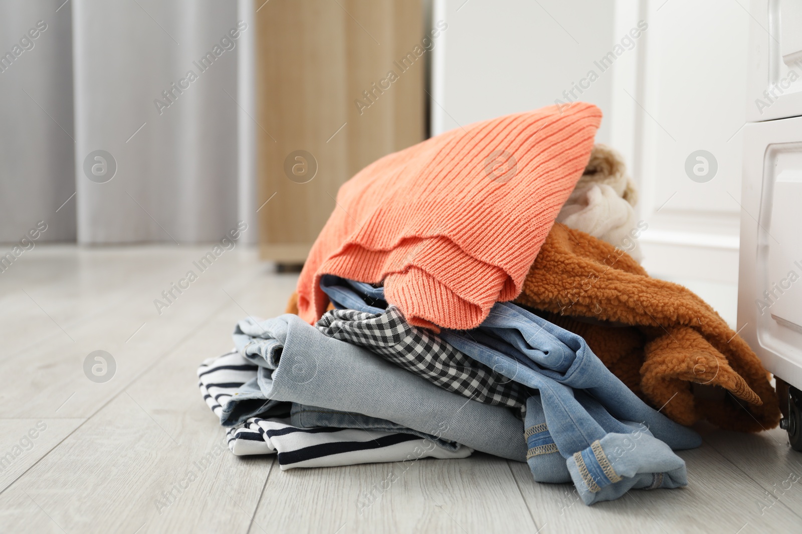 Photo of Pile of different used clothes on floor indoors. Space for text