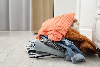 Photo of Pile of different used clothes on floor indoors. Space for text