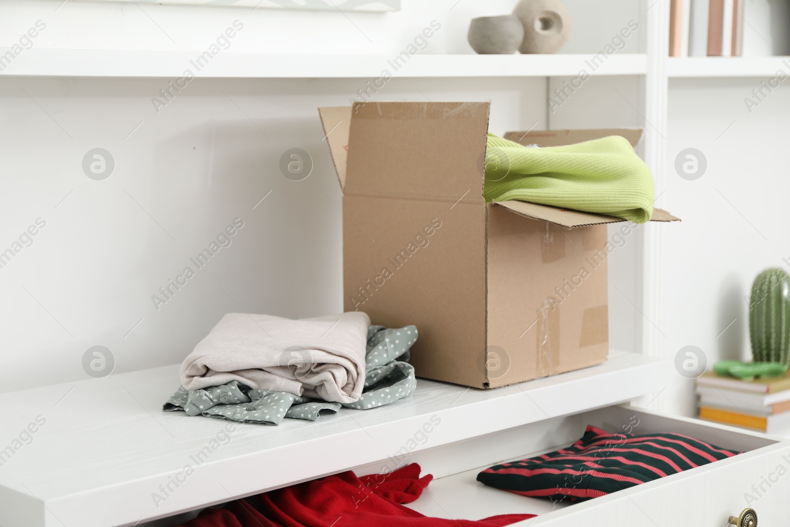 Photo of Used clothes and box on chest of drawers indoors