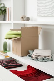 Photo of Used clothes and box on chest of drawers indoors