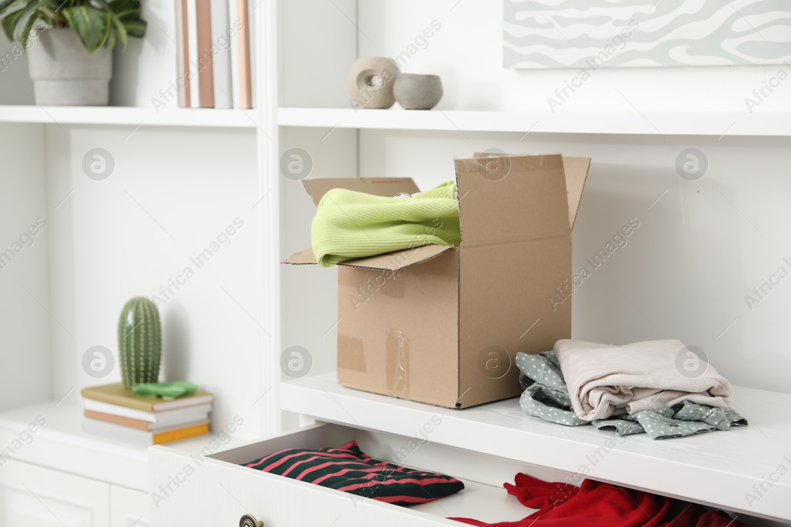 Photo of Used clothes and box on chest of drawers indoors