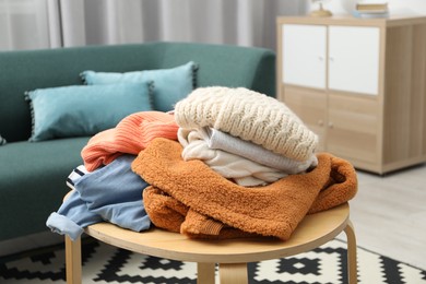 Photo of Pile of different used clothes on coffee table indoors, closeup