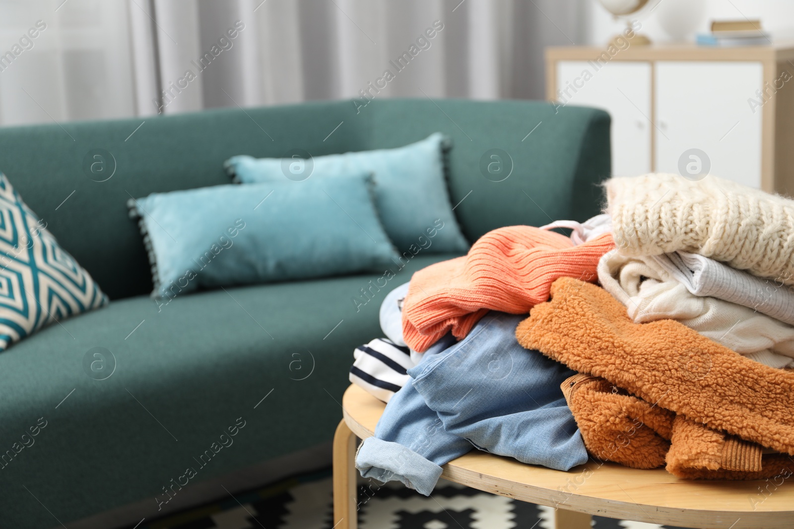 Photo of Pile of different used clothes on coffee table indoors, closeup. Space for text