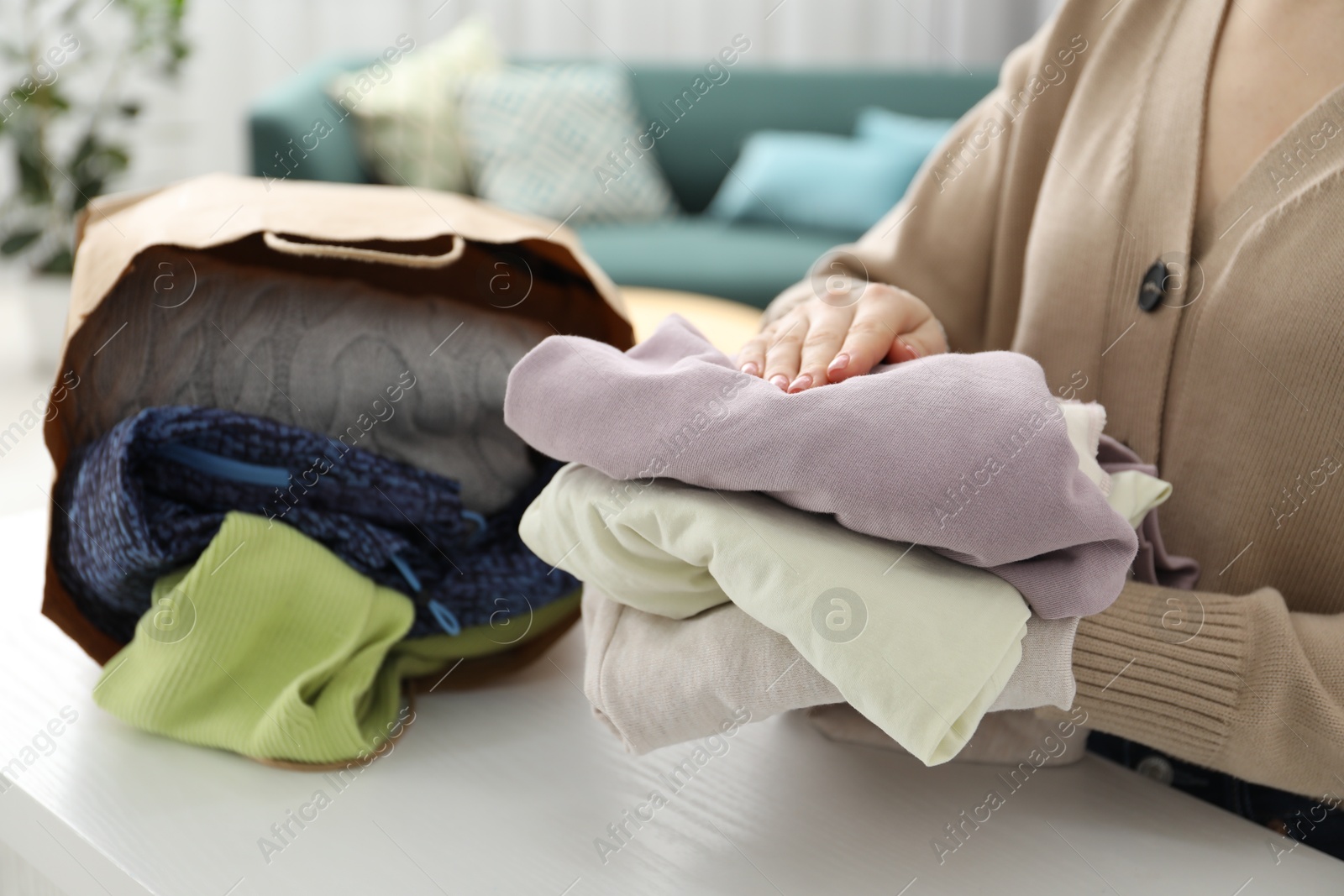 Photo of Woman organizing used clothes at white counter indoors, closeup