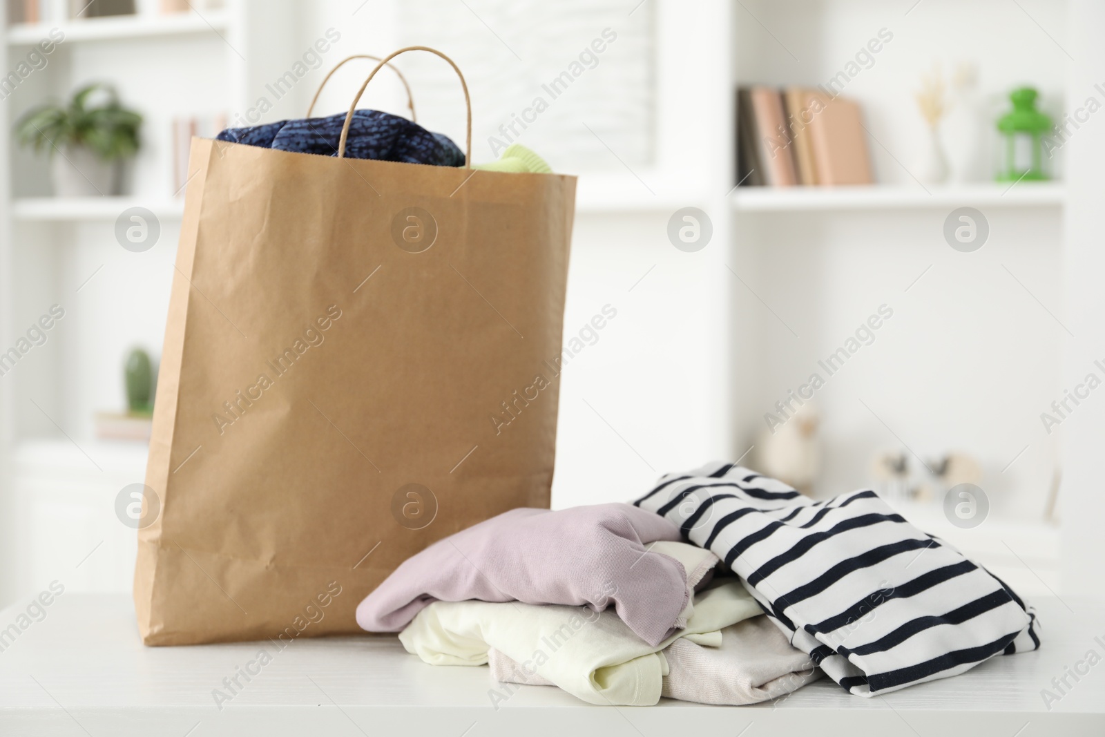 Photo of Used clothes and paper bag on white counter indoors, closeup