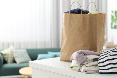 Photo of Used clothes and paper bag on chest of drawers indoors, closeup. Space for text