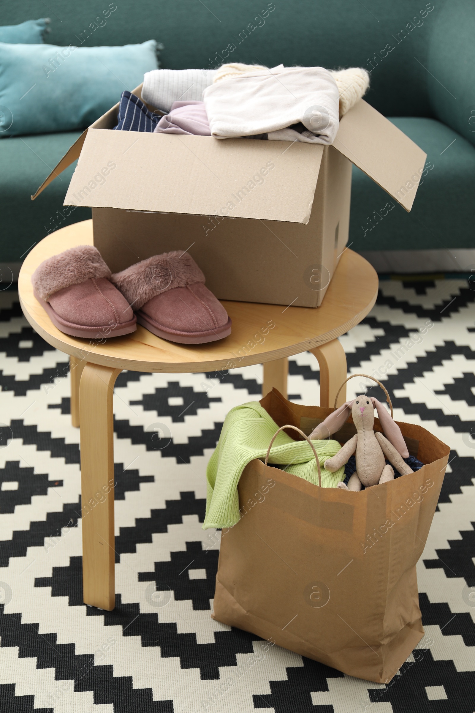 Photo of Different used clothes in box and paper bag indoors