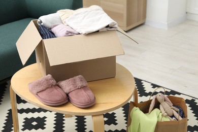 Photo of Different used clothes in box on coffee table indoors