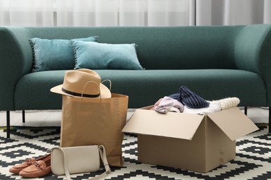 Photo of Used clothes, paper bag and box on floor indoors