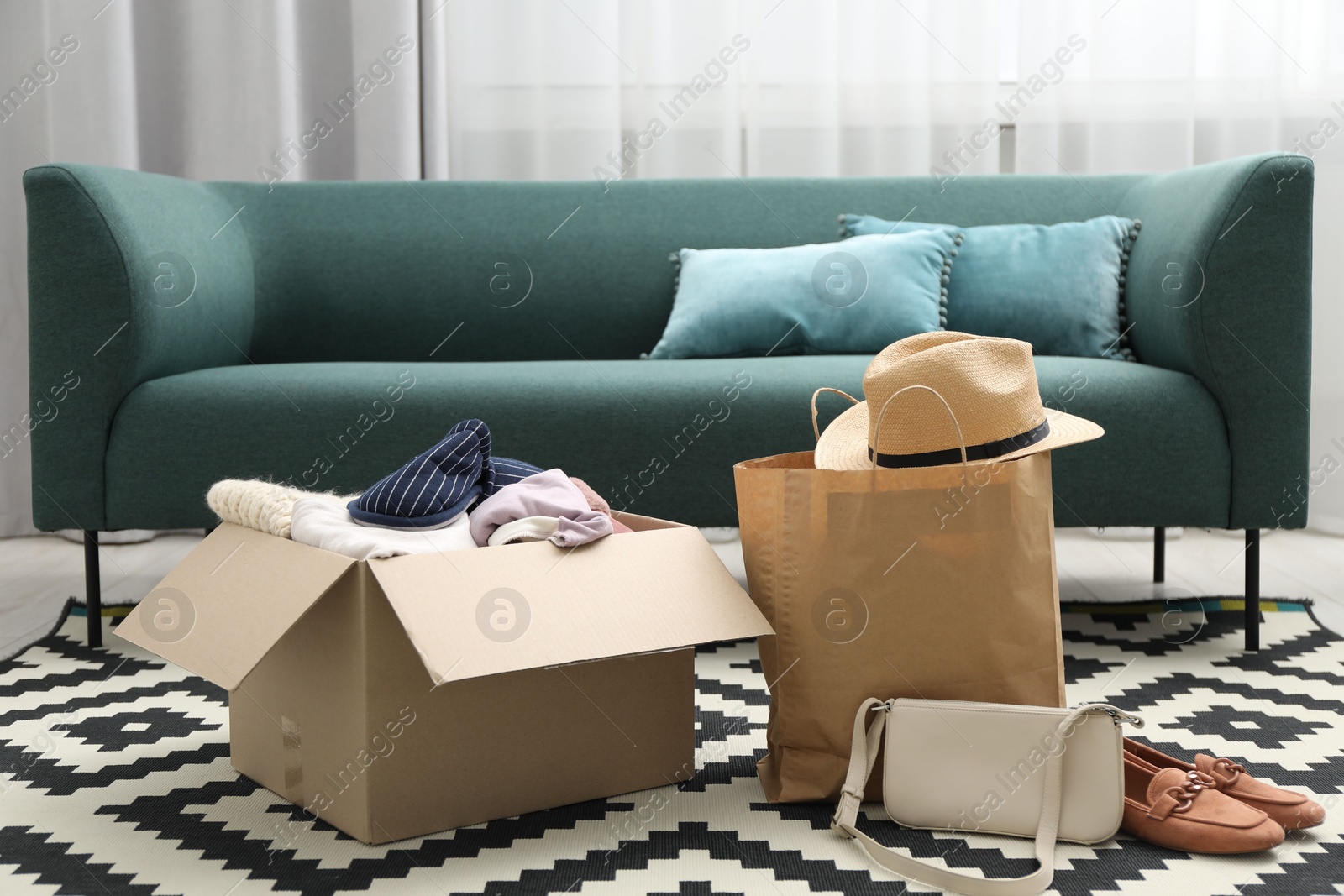 Photo of Used clothes, paper bag and box on floor indoors