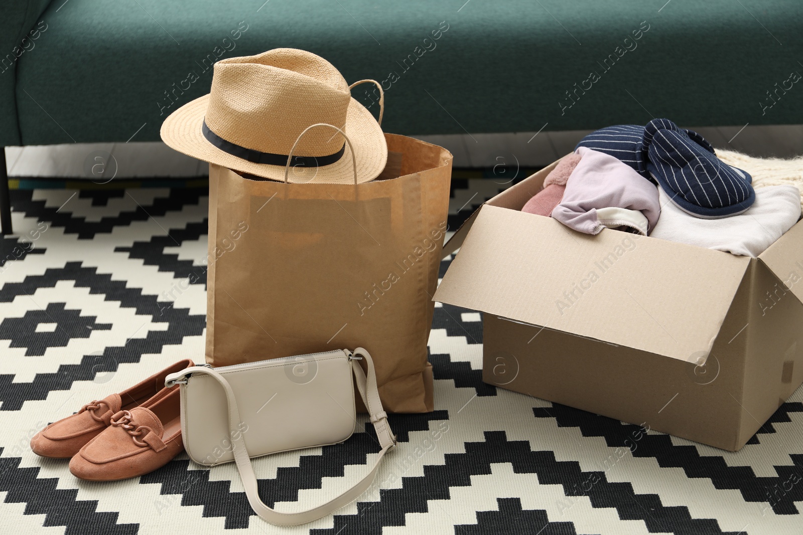 Photo of Used clothes, paper bag and box on floor indoors