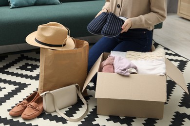 Photo of Woman with used clothes on floor indoors, closeup