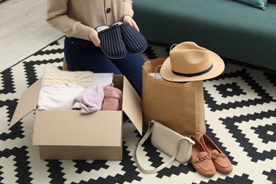 Photo of Woman with used clothes on floor indoors, closeup