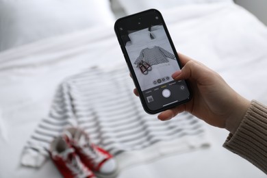 Photo of Woman with smartphone taking photo of her used clothes indoors, selective focus