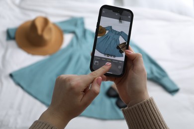 Photo of Woman with smartphone taking photo of her used clothes indoors, selective focus