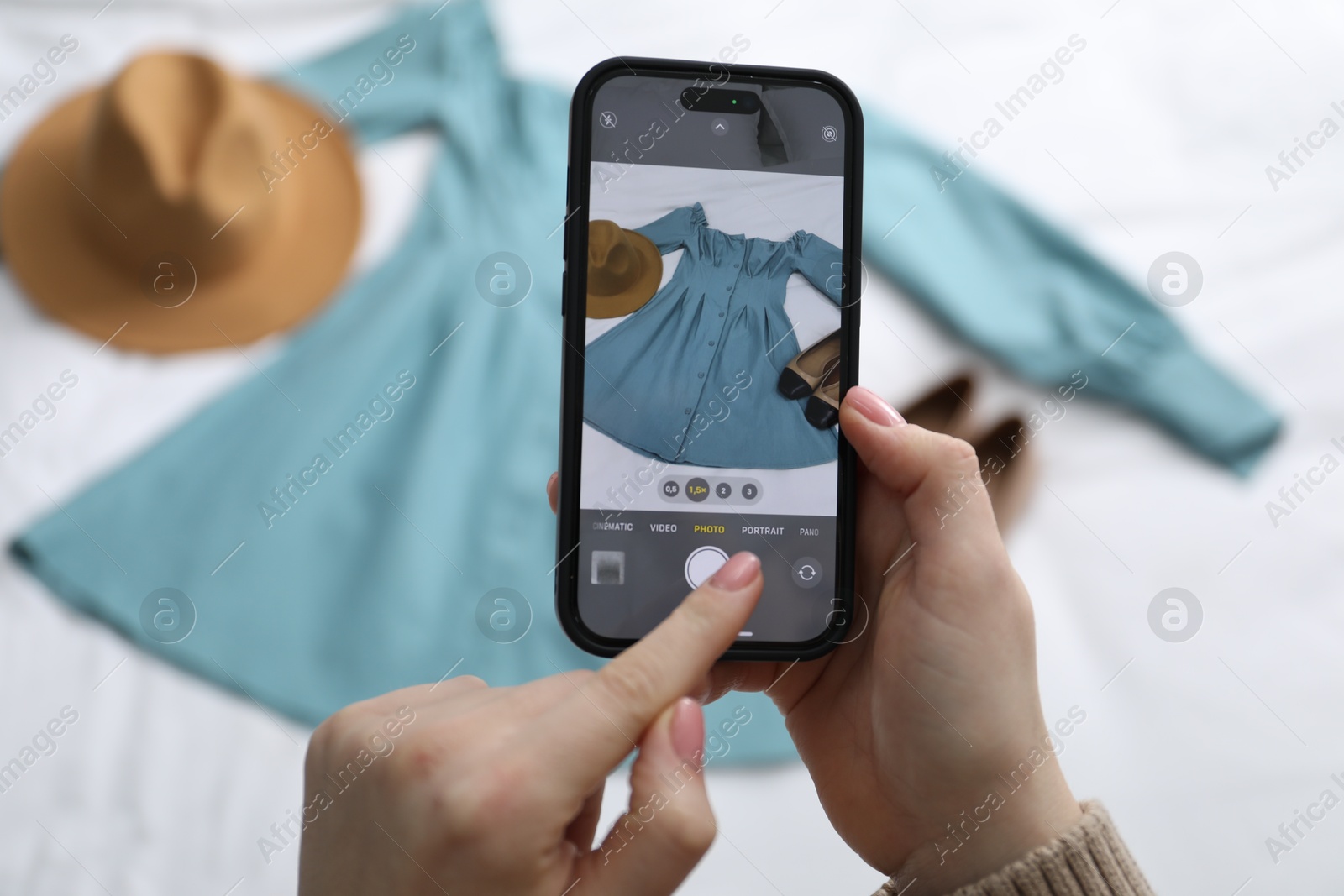 Photo of Woman with smartphone taking photo of her used clothes indoors, selective focus