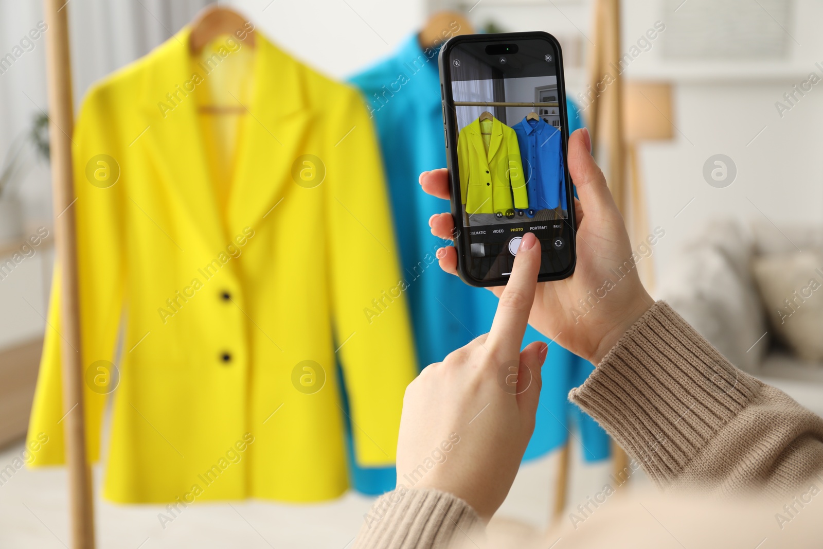 Photo of Woman with smartphone taking photo of her used clothes indoors, selective focus