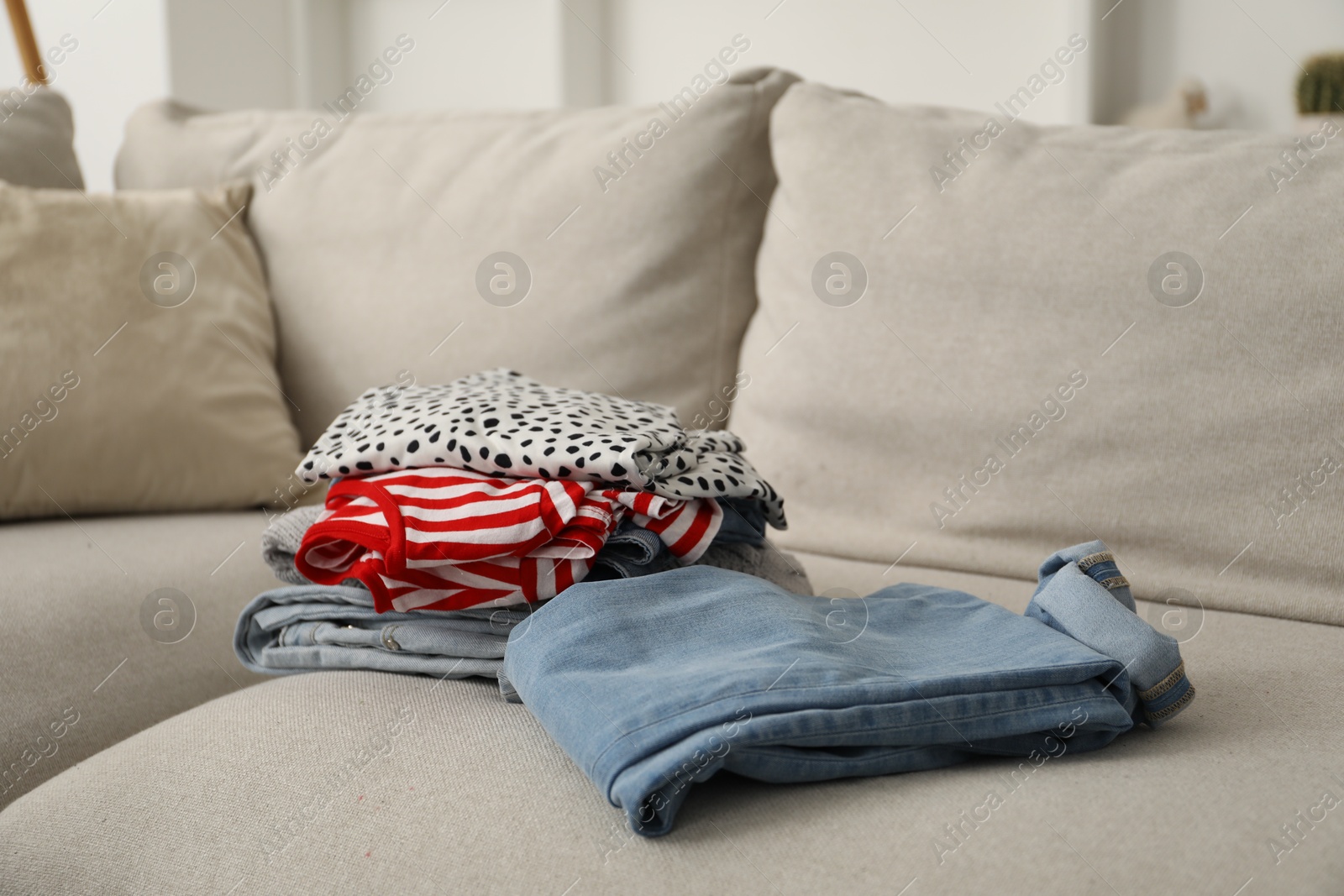 Photo of Different used clothes on sofa indoors, closeup