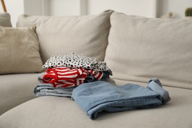 Photo of Different used clothes on sofa indoors, closeup