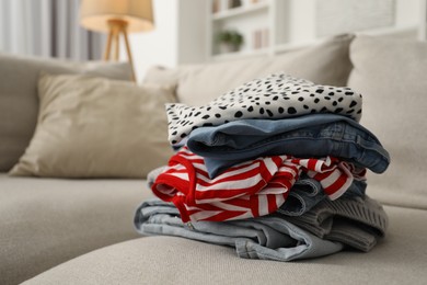 Photo of Stack of different used clothes on sofa indoors, closeup. Space for text