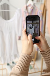 Photo of Woman with smartphone taking photo of her used clothes indoors, selective focus