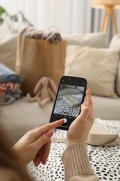 Photo of Reuse and donation of used clothes. Woman with smartphone taking photo of her bag indoors, selective focus