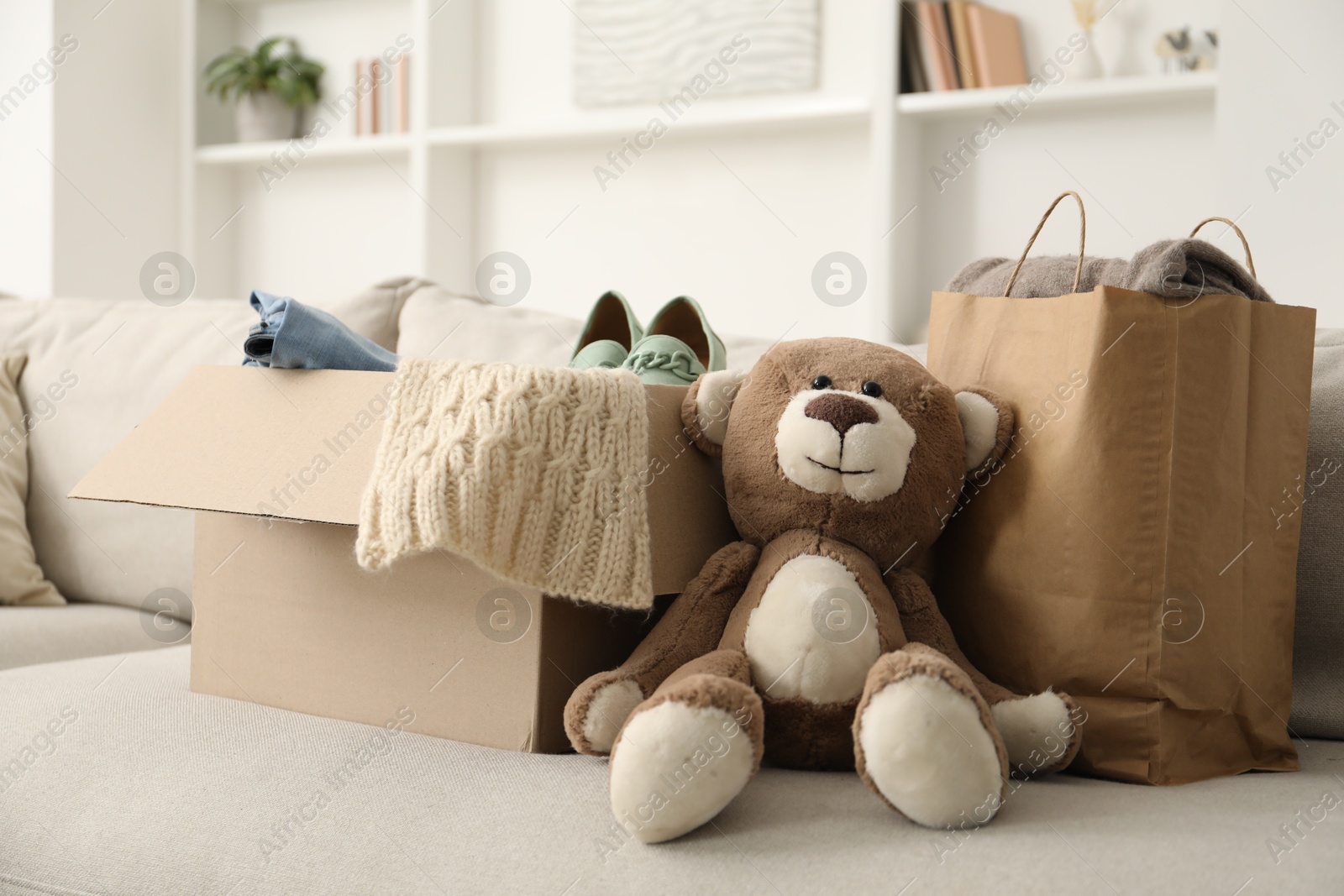 Photo of Used clothes in paper bag and box on sofa indoors