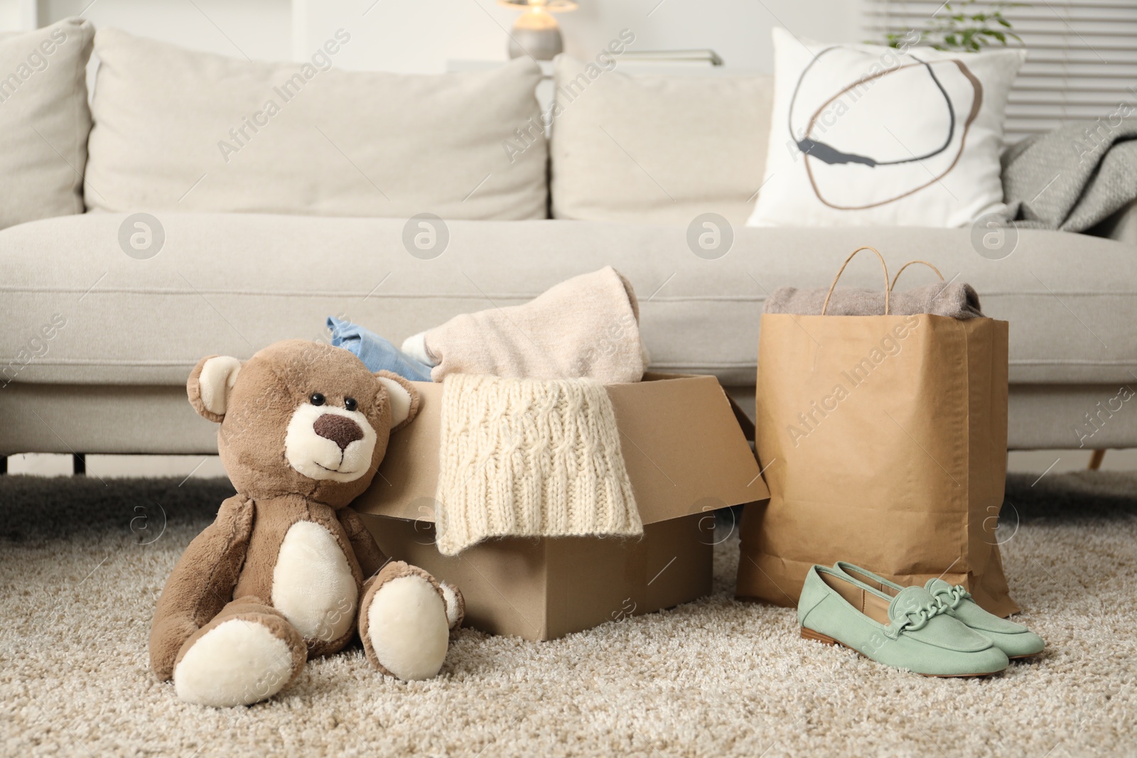 Photo of Used clothes, toy, paper bag and box on floor indoors