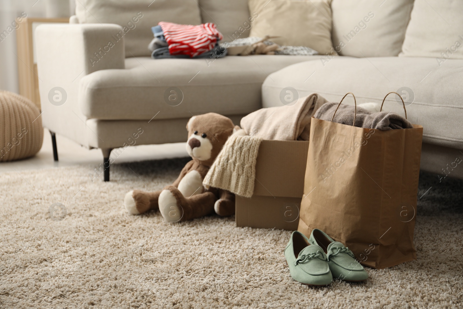 Photo of Used clothes, toy, paper bag and box on floor indoors, space for text