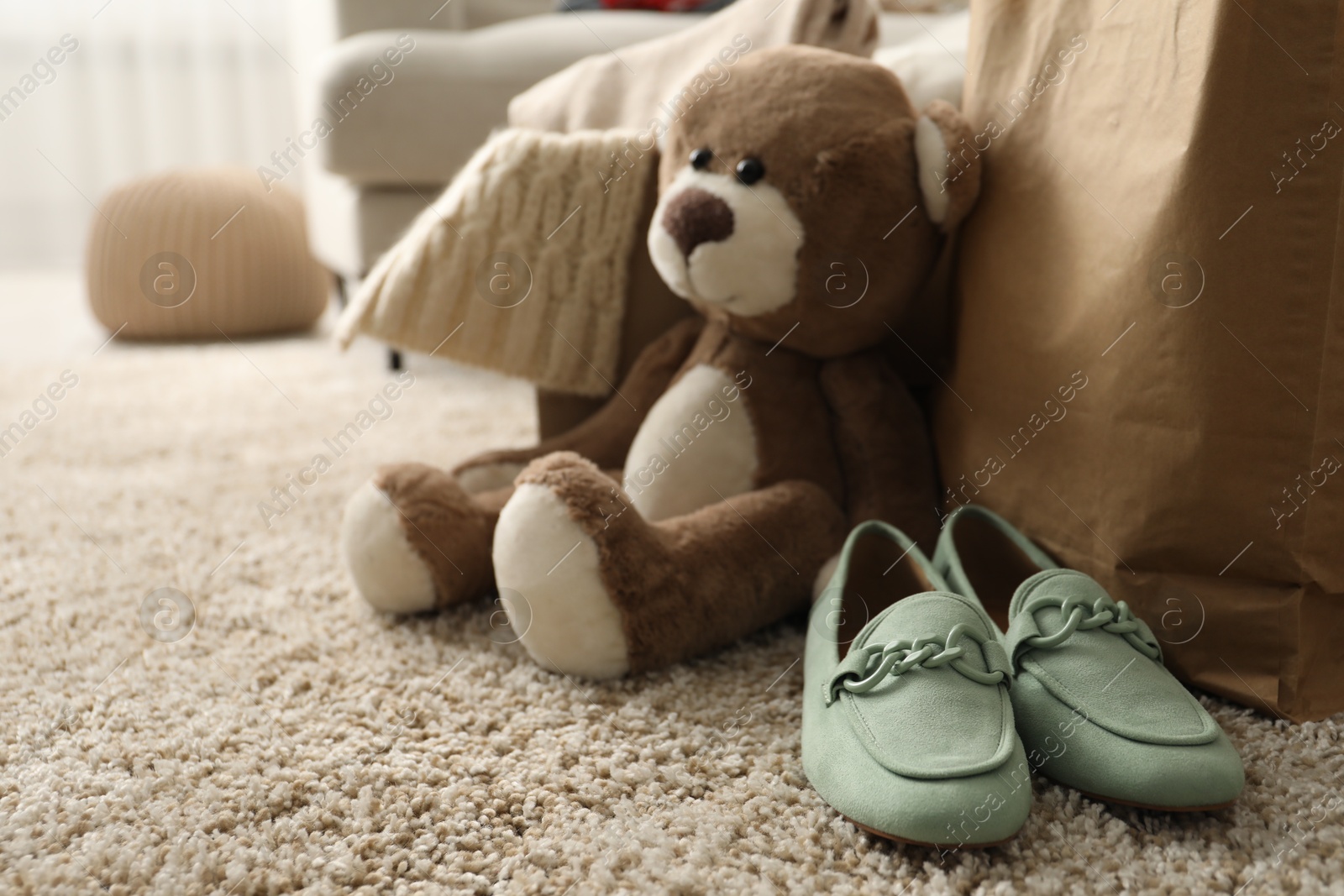 Photo of Used clothes, toy and shoes on floor indoors, closeup with space for text