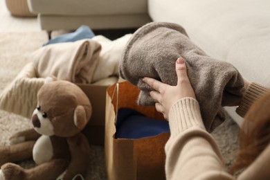 Photo of Woman stacking used clothes at home, closeup