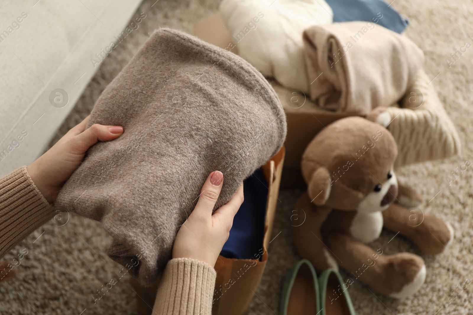 Photo of Woman stacking used clothes at home, closeup