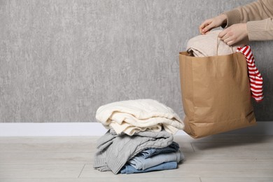 Photo of Woman with used clothes near grey wall indoors, closeup. Space for text