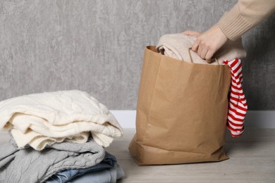 Photo of Woman with used clothes on floor near grey wall, closeup