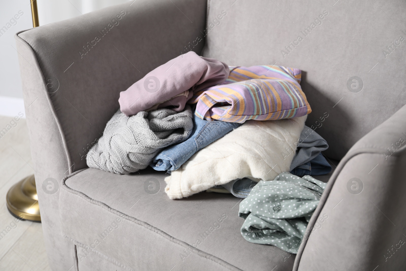 Photo of Pile of different used clothes on armchair indoors