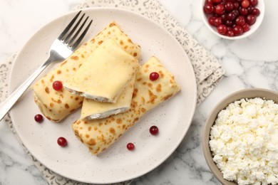 Photo of Delicious rolled crepes with cottage cheese, raisins and cranberries on white marble table, flat lay