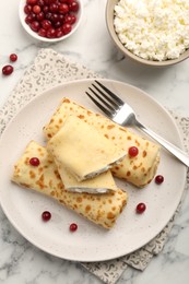 Photo of Delicious rolled crepes with cottage cheese, raisins and cranberries on white marble table, flat lay