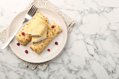 Photo of Delicious rolled crepes with cottage cheese, raisins and cranberries on white marble table, top view. Space for text