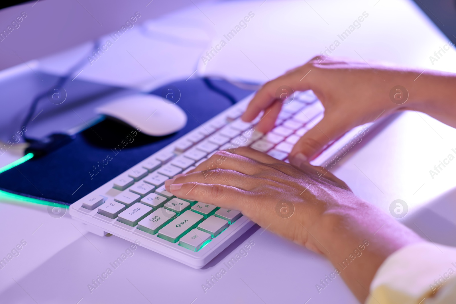 Photo of Woman using computer keyboard at white table indoors, closeup