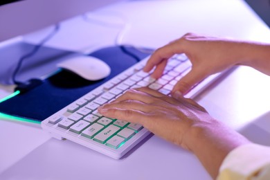 Photo of Woman using computer keyboard at white table indoors, closeup