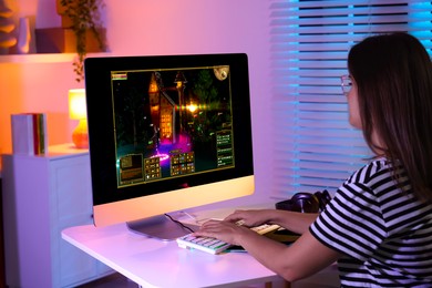 Photo of Woman playing video game with keyboard at table indoors