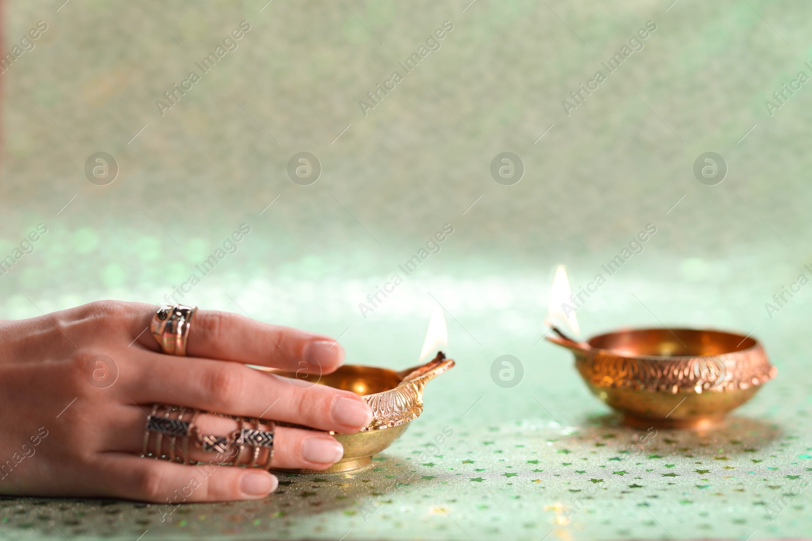 Photo of Diwali celebration. Woman with lit diya lamp on color background, closeup