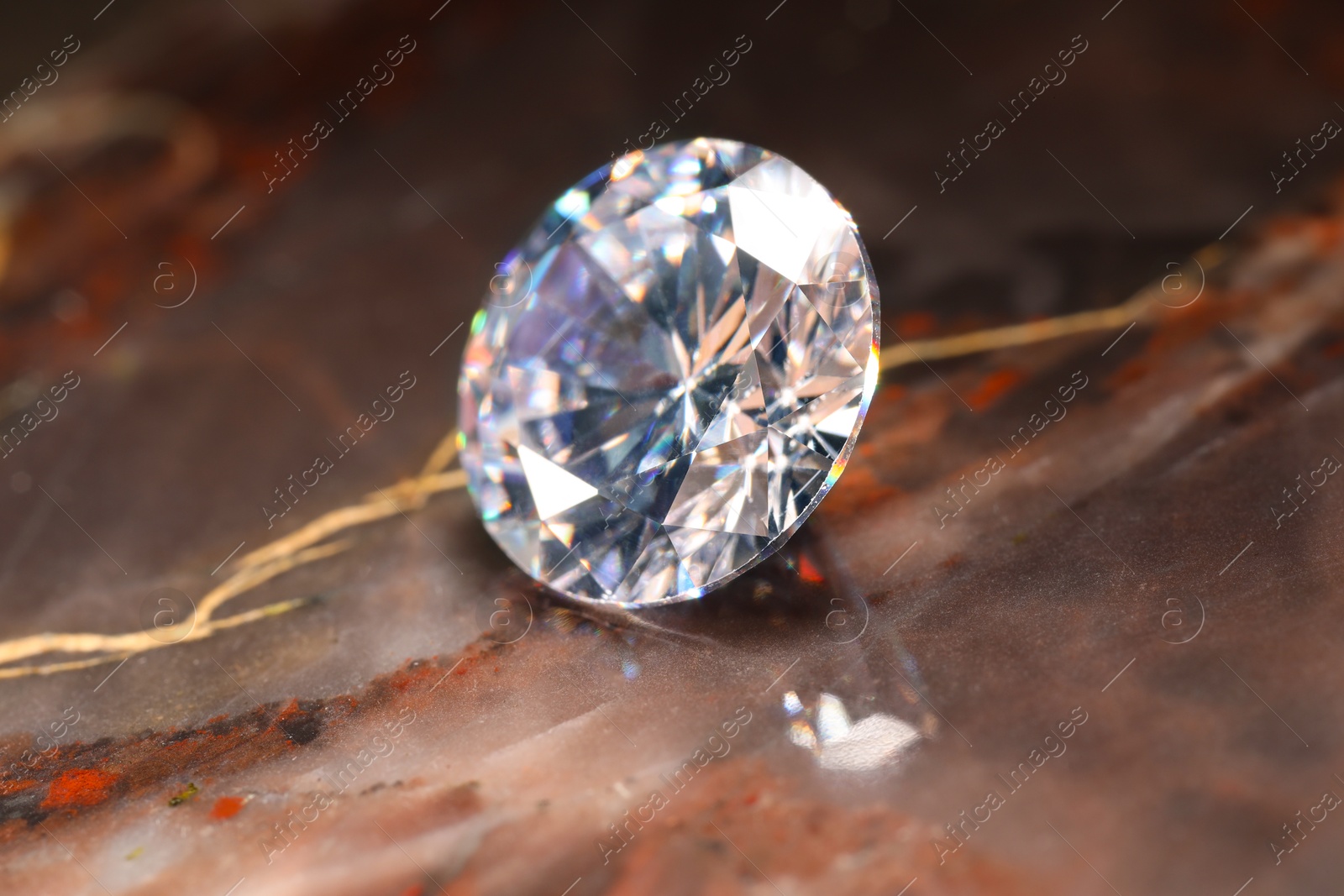 Photo of Beautiful shiny gemstone on brown marble surface, closeup