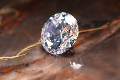 Photo of Beautiful shiny gemstone on brown marble surface, closeup