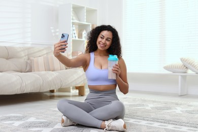 Photo of Beautiful woman taking selfie with protein shake at home