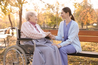 Caregiver with elderly woman in wheelchair at park