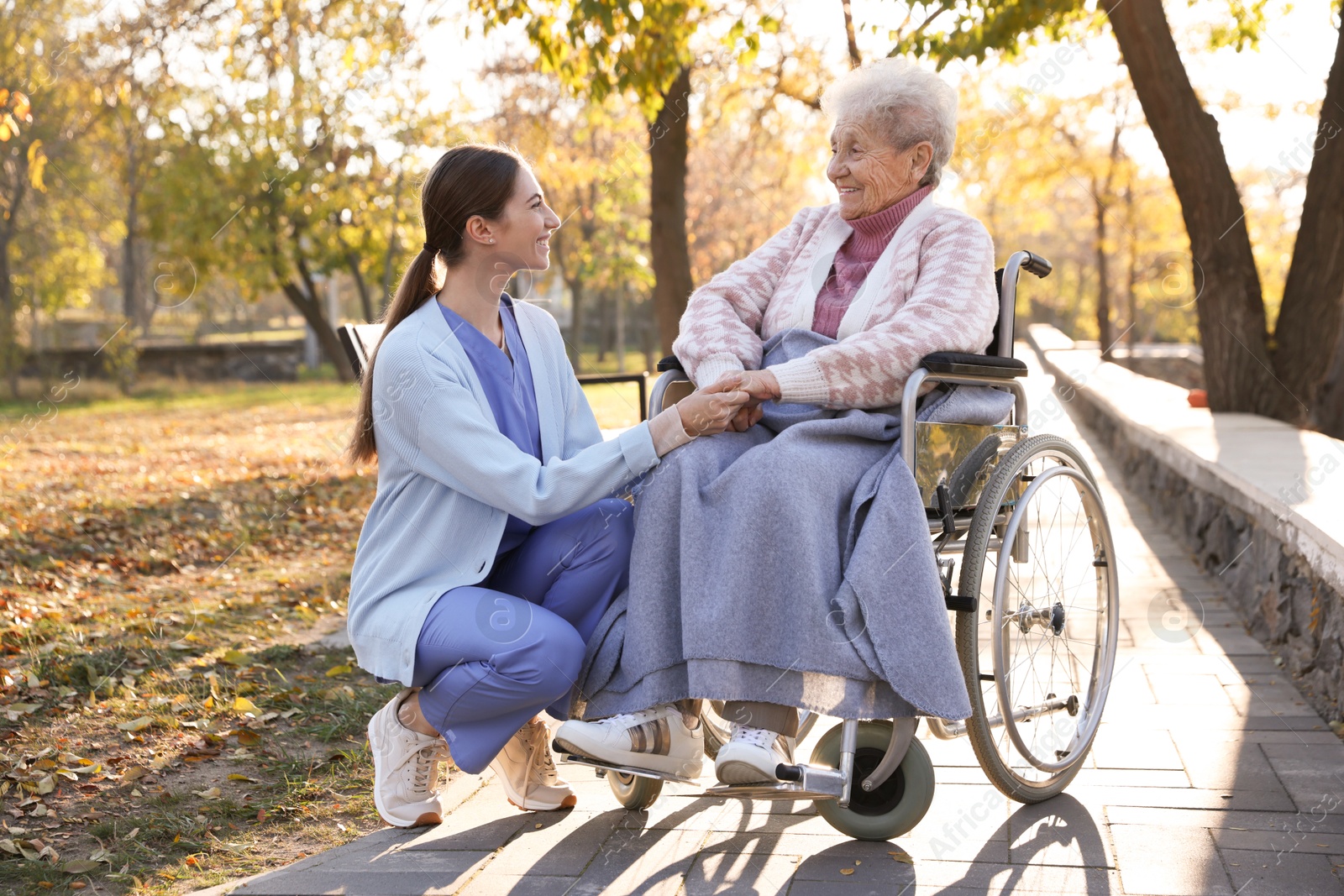 Photo of Caregiver with elderly woman in wheelchair at park